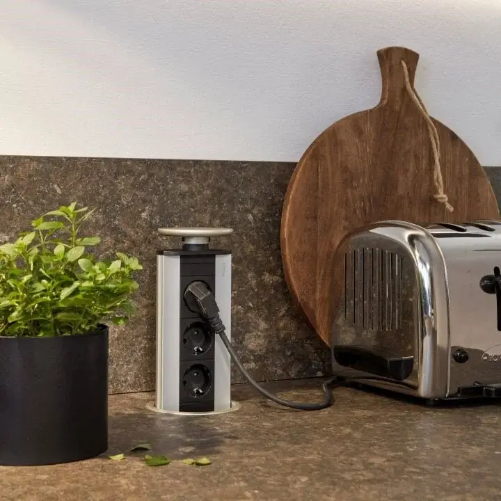 Versenkbare Steckdosenleiste auf Küchenarbeitsplatte neben Toaster – praktische Anschlusslösung für moderne Küchen mit Alltag.