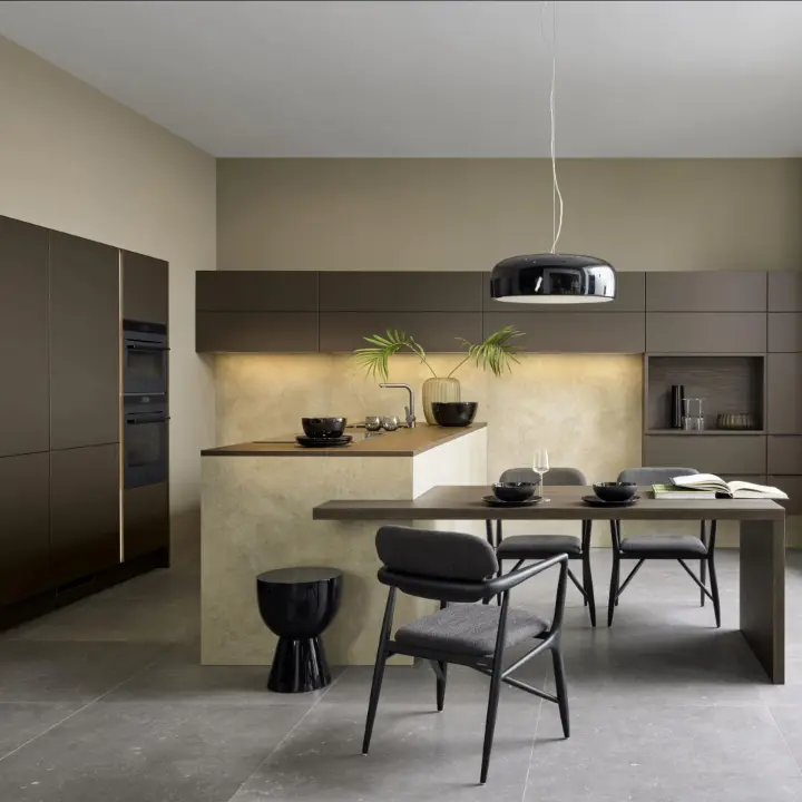 Moderne Wohnküche in warmen Brauntönen mit matten Fronten, Insel in Steinoptik, Esstisch und schwarzer Pendelleuchte – eleganter Materialmix von LS Küchen.