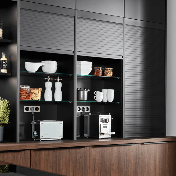 Designküche mit geschlossenem Jalousieschrank, Glasböden und Geräten hinter Rollfront – ordentliche, moderne Stauraumlösung.
